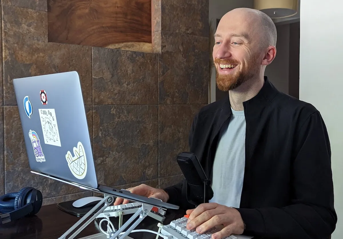 Tam smiling while working on a laptop